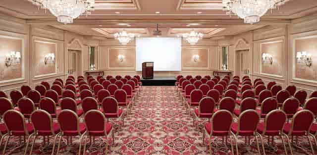 Elegant meeting space with red chairs and chandelier in Regent Berlin for conferences.