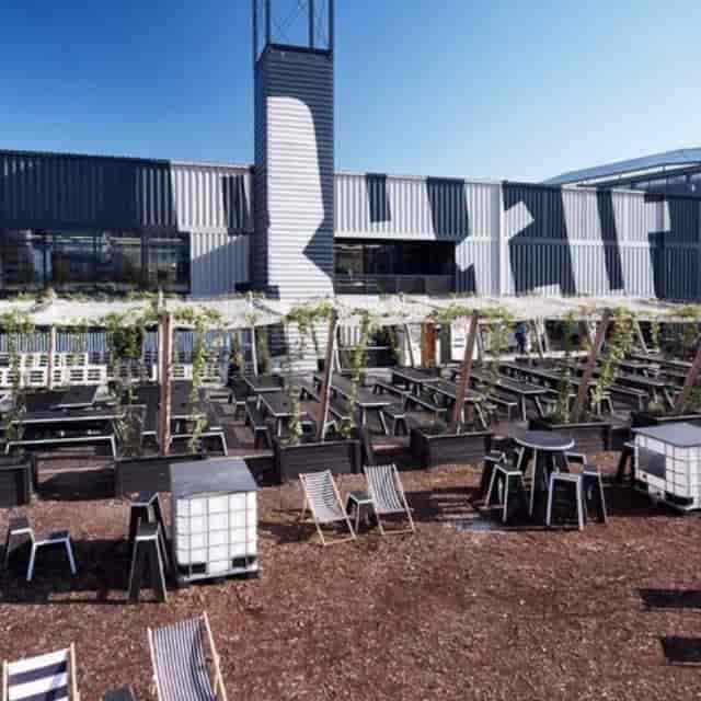 Modern beer garden with black wooden tables for networking events in BRLO BRWHOUSE.