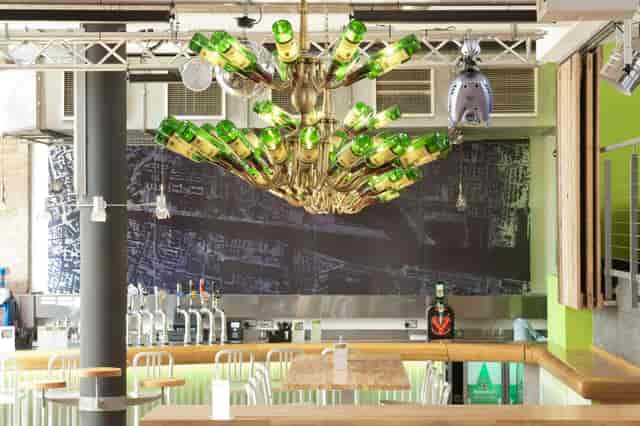 Vibrant bar space with green bottle chandelier for networking events and gatherings.