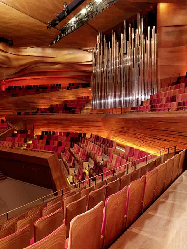 Sophisticated concert hall with tiered wooden seating for optimal acoustics and ambiance.