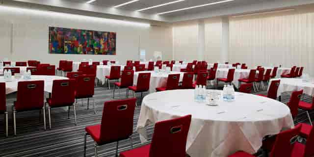 Conference Room in DIS Copenhagen with round tables and vibrant red chairs for meetings or banquets.