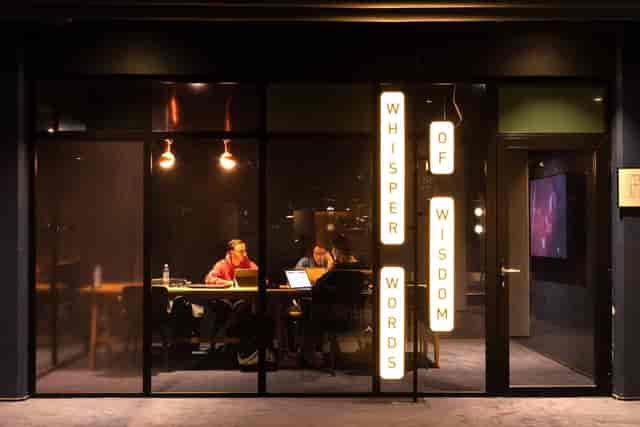 Modern meeting space "Whisper Words of Wisdom" with glass walls for collaboration.