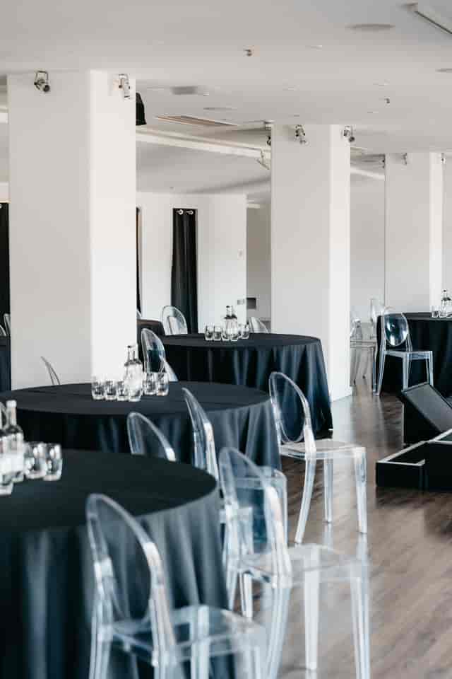 Modern minimalist event setup with black linens and ghost chairs for corporate gala or reception.