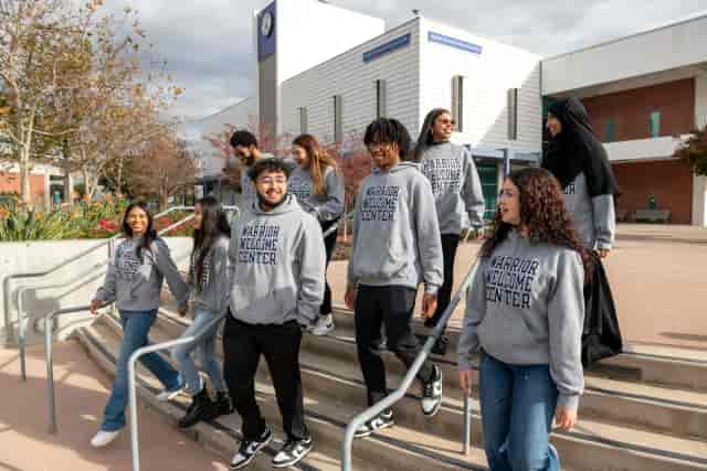 Diverse group in hoodies walking at El Camino College for team-building event.
