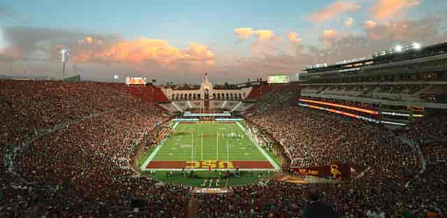 Los Angeles Coliseum filled with fans at sunset during a major sporting event.