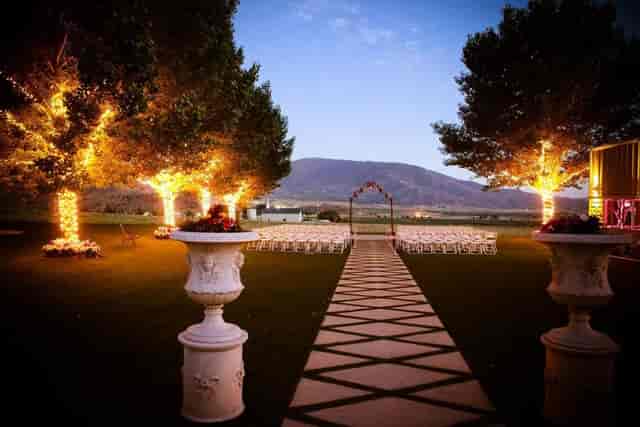 "Outdoor wedding venue at Cielo Rose Garden with illuminated altar and elegant seating."