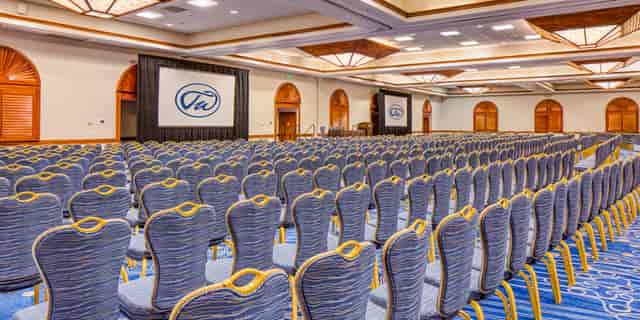 Breakout Rooms at TradeWinds Resort set for a conference, featuring blue chairs and screens.