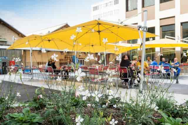 Outdoor restaurant event space with yellow umbrellas, ideal for networking and casual gatherings.