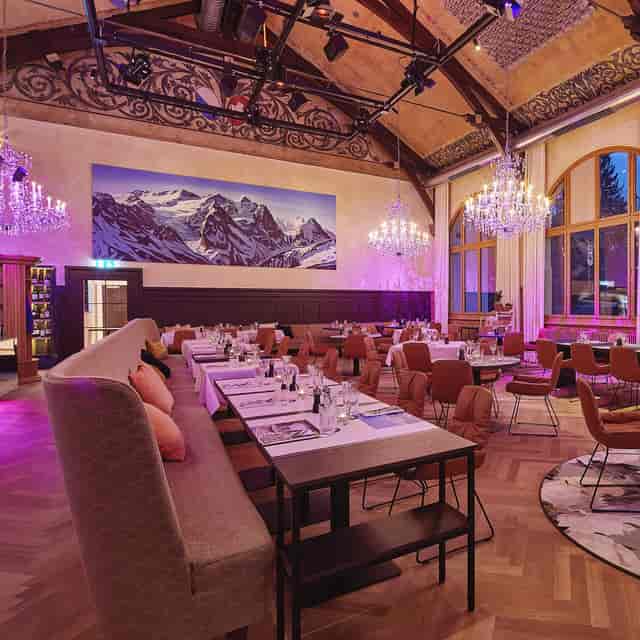 Elegant event space at Gasthaus Albisgütli with chandelier and mountain mural for gatherings.