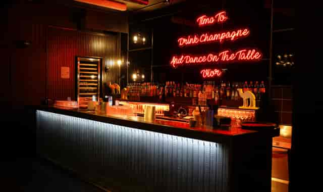 Stylish urban restaurant bar with neon sign, ideal for upscale events and gatherings.