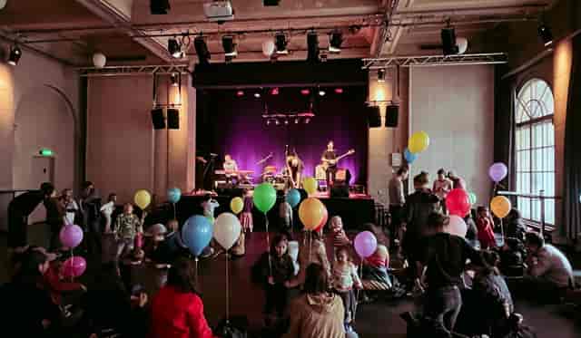 Vibrant Kulturmarkt foyer event with musicians, balloons, and families celebrating together.