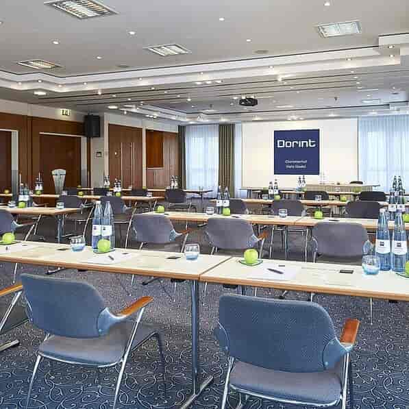 Modern corporate meeting room with natural lighting, tables, and branding at Dorint Tagungshotels.