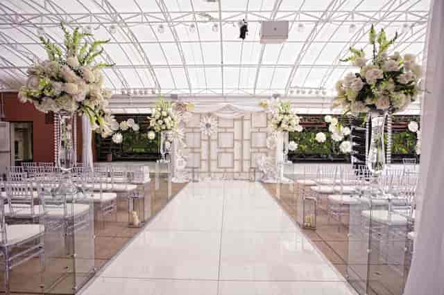 Elegant wedding ceremony in Banquet Hall, featuring floral arrangements and modern acrylic chairs.
