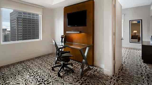 Modern meeting room with glass desk and city views at The Sam Houston, Curio Collection.
