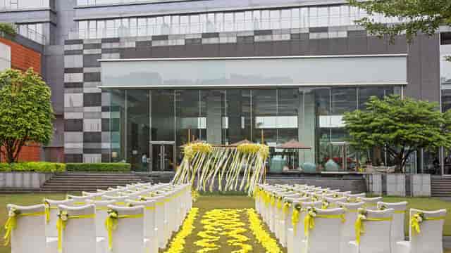 Outdoor wedding venue at Crowne Plaza Guangzhou with yellow ribbon chairs and floral decor.