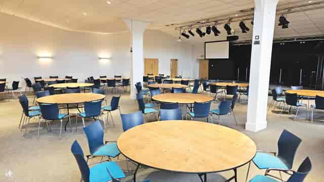 Auditorium with round tables, ideal for workshops and networking events.