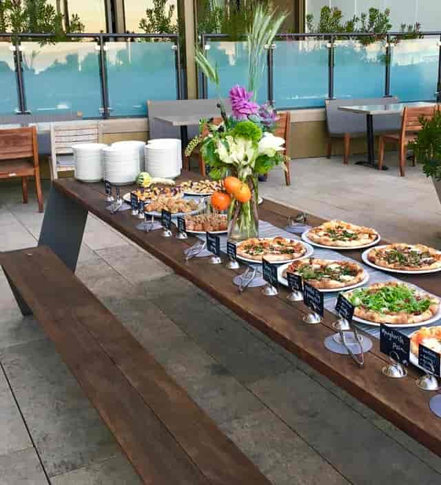 Outdoor patio buffet with gourmet pizzas and fresh salads for networking events.
