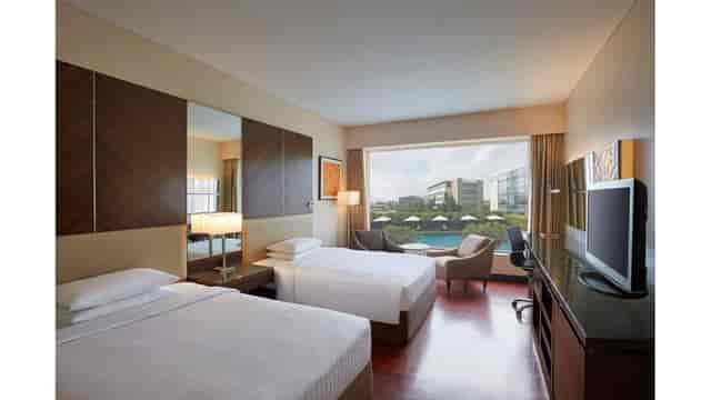 Hotel room with twin beds and large window, perfect for conference attendees at Mumbai Airport.