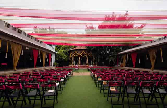 Outdoor conference hall with elegant black chairs and burgundy sashes for weddings.