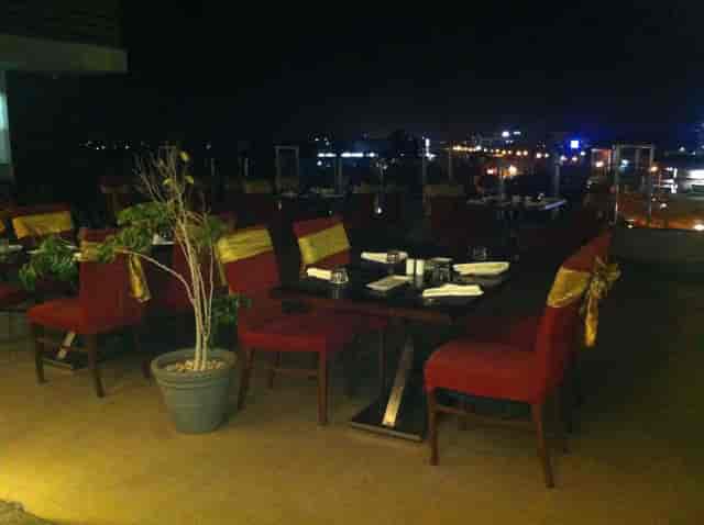 Elegant rooftop restaurant with red chairs, ideal for evening events and gatherings.