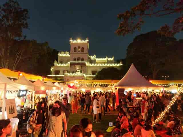 Vibrant outdoor festival at Jayamahal Palace's lit Boardroom I with lively crowds.