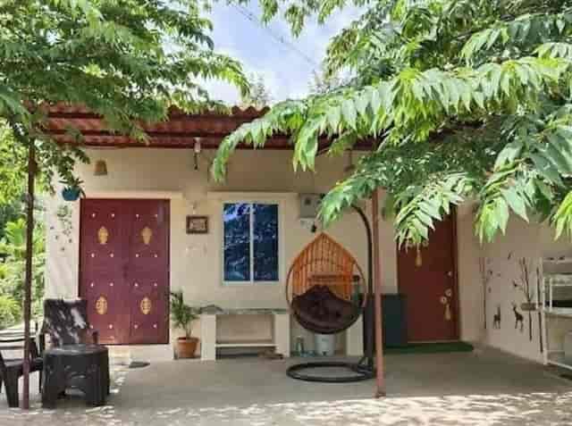 Games Room at Sattva Farmstay: cozy outdoor space for gatherings with greenery and hanging chair.