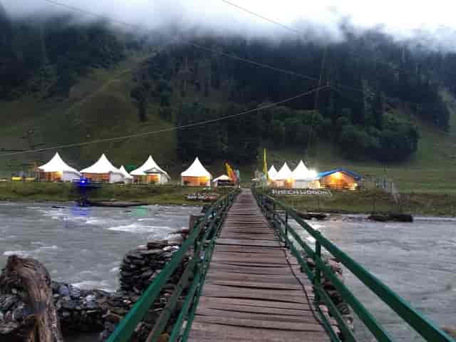 Outdoor event setup at Sheen Woods Resort with white tents by a serene river.