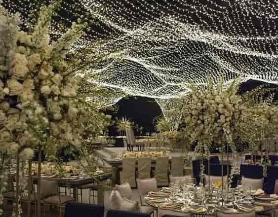 Outdoor garden venue with floral decor and twinkling lights for weddings and gatherings.