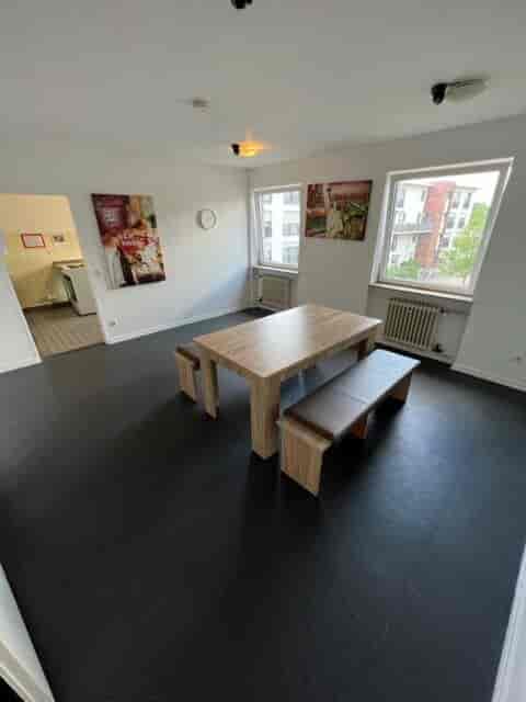 Inviting lounge with wooden table and benches for team meetings at MLKH Studentenwohnheim.