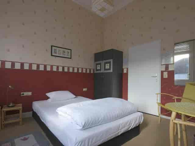 Hotel am Berg garden area, simple room with single bed for quiet conference breaks.
