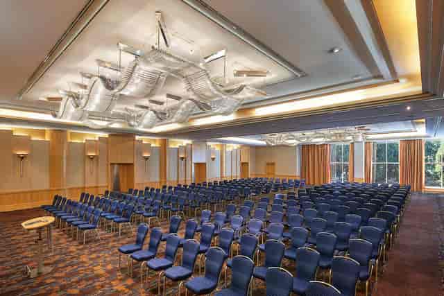 Spacious banquet hall with blue chairs, ideal for conferences and presentations in Frankfurt.