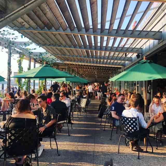 Vibrant outdoor dining patio with green parasols, perfect for social events and networking.