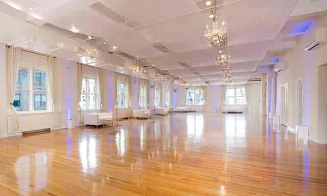 "Elegant banquet hall with polished wood floors and chandeliers, perfect for weddings and events."