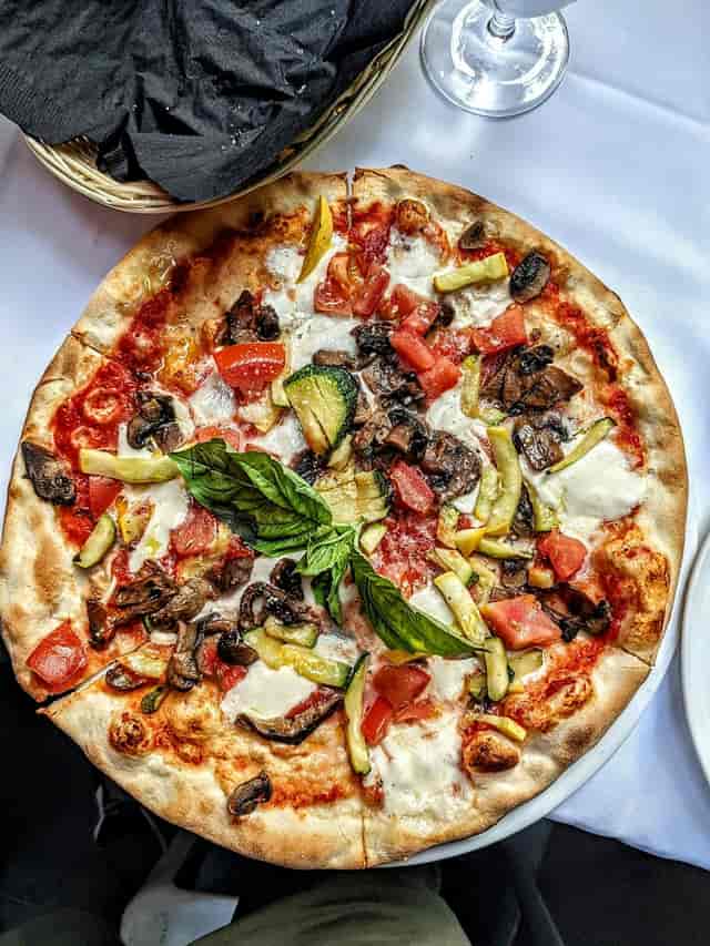 Vibrant pizza with fresh veggies at Arte Cafe, ideal for events and catering.