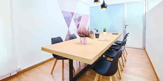 Modern meeting room with wooden table and black chairs for collaborative sessions.