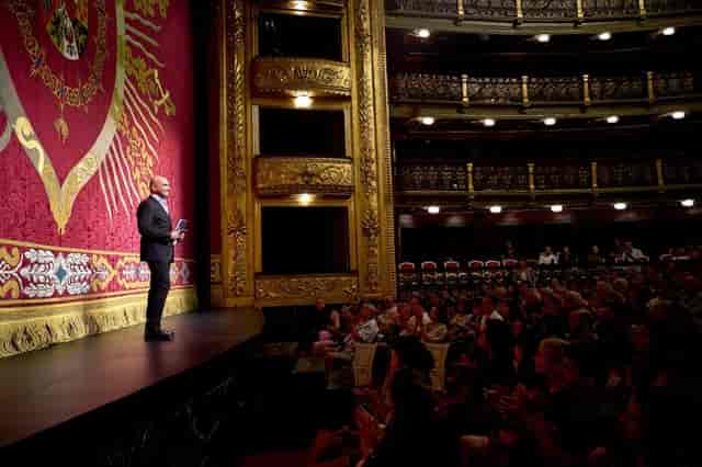 Speaker addressing audience in Teatro Español’s ornate Sala Principal for cultural events.