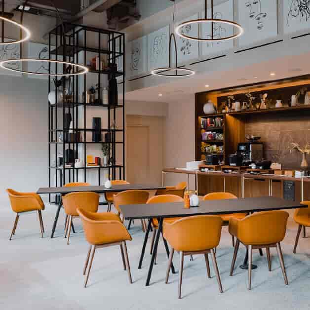 Modern lounge with orange chairs, ideal for professional meetings and events.