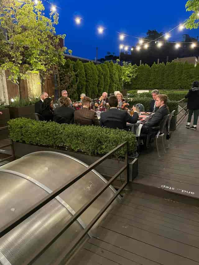 Outdoor dining setup under string lights for a corporate event at Fathom Gallery.