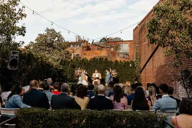 Intimate outdoor wedding ceremony at Fathom Gallery with greenery and string lights.