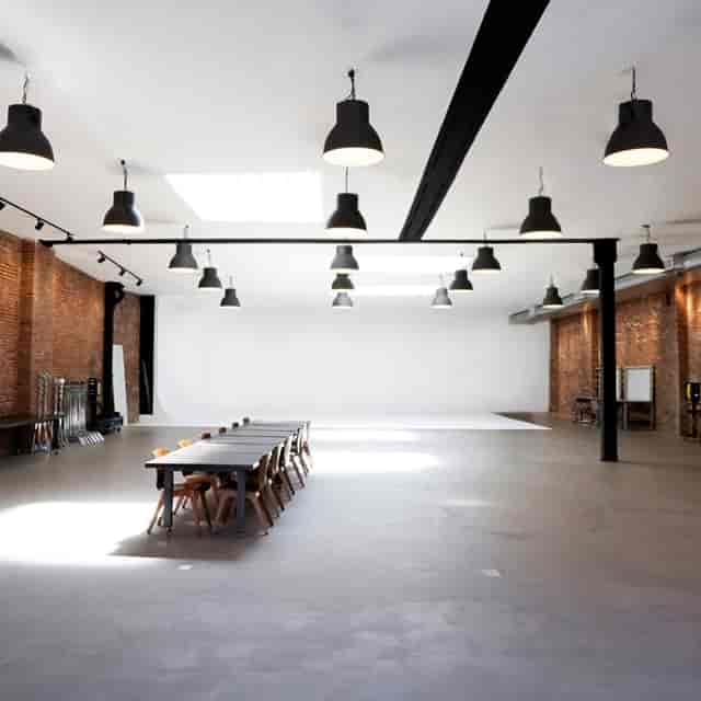 Spacious industrial studio with large windows for corporate events and workshops.