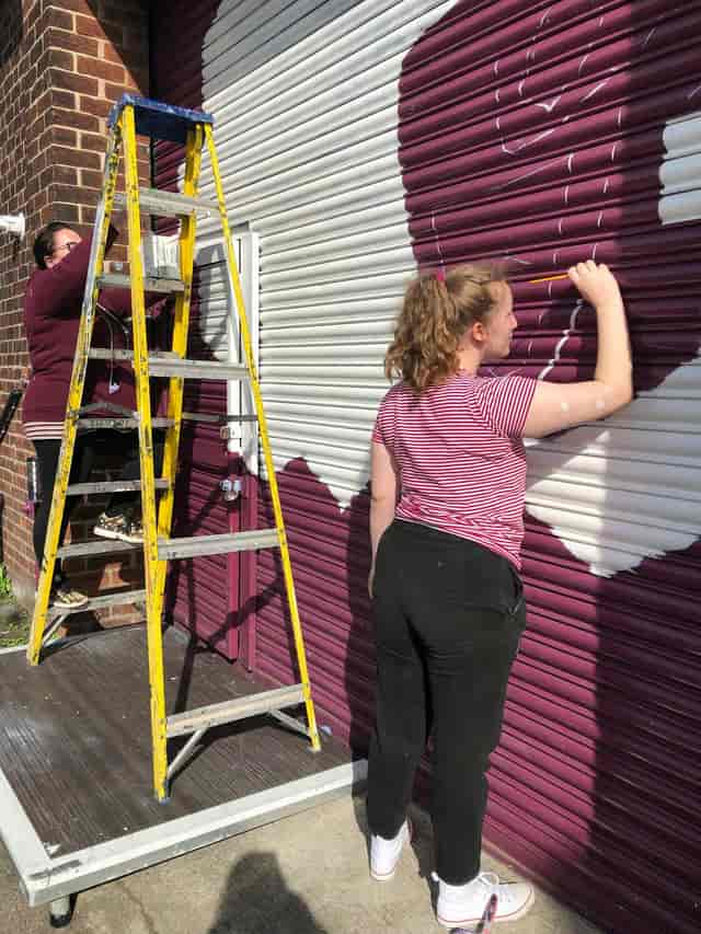 NWTAC Theatre team collaborates on mural project for vibrant community event backdrop.