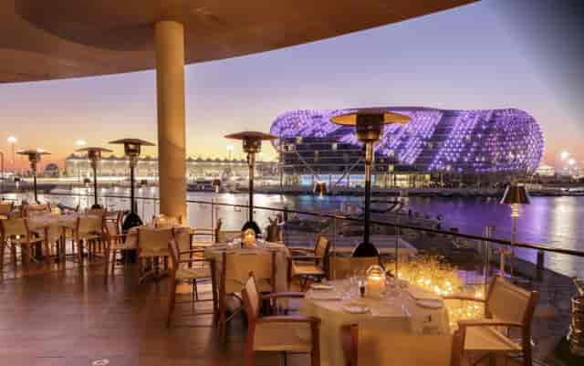 Outdoor dining at Cipriani Yas Island, elegant setup by waterfront for upscale events.