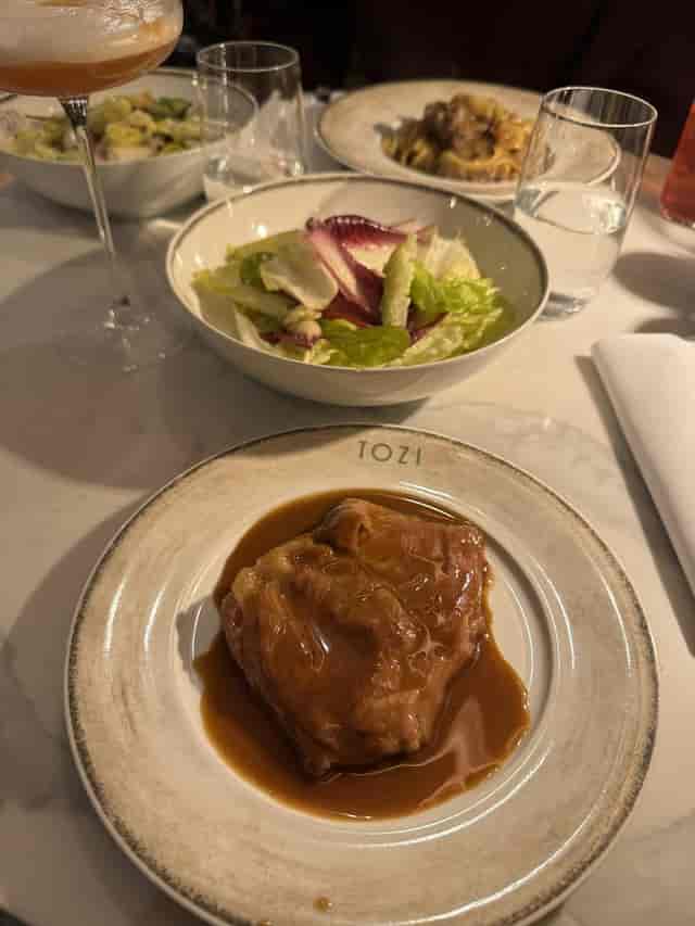 Dish with meat in sauce and salad at Tozi Amsterdam for events and catering.