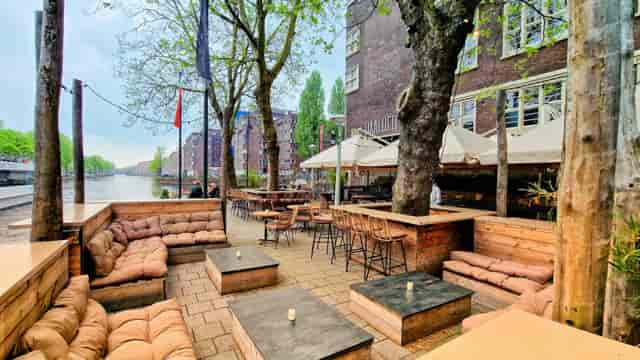 Atrium outdoor event space with cozy seating by waterway for gatherings and networking.