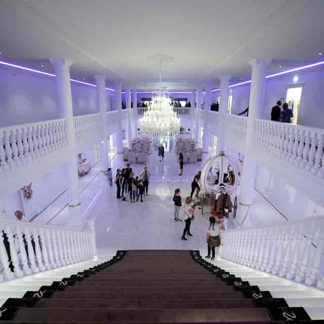 Elegant ballroom with grand staircase, perfect for receptions and gala events.