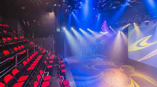 Versatile Melkweg event space with tiered seating and dynamic stage lighting.