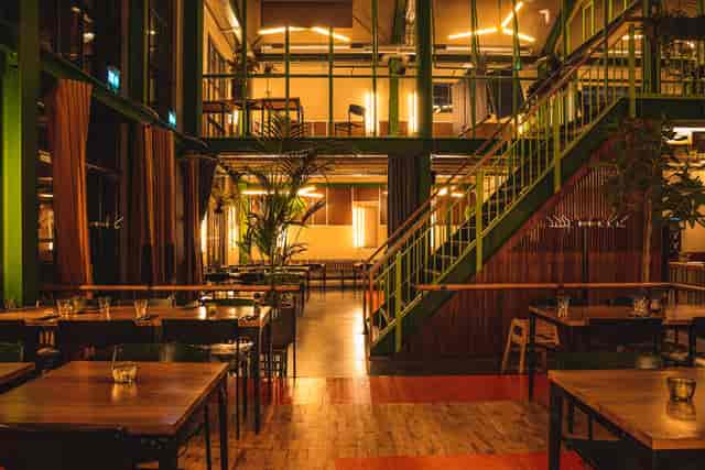 Spacious IJver Amsterdam restaurant with wooden tables, ideal for events and workshops.
