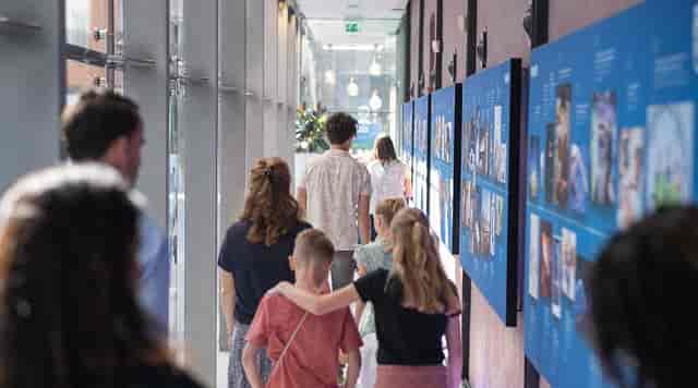 Group networking in well-lit Philips Museum corridor with visual displays.
