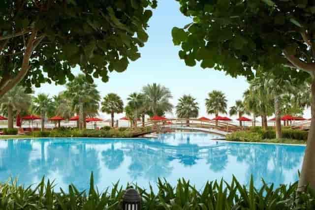 Poolside gardens at Khalidiya Palace with lush greenery, ideal for networking events.