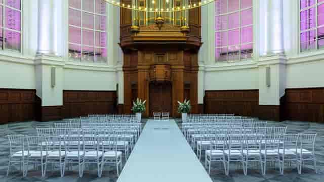 Elegant Renaissance Amsterdam Hotel meeting room with white chairs set for a wedding ceremony.